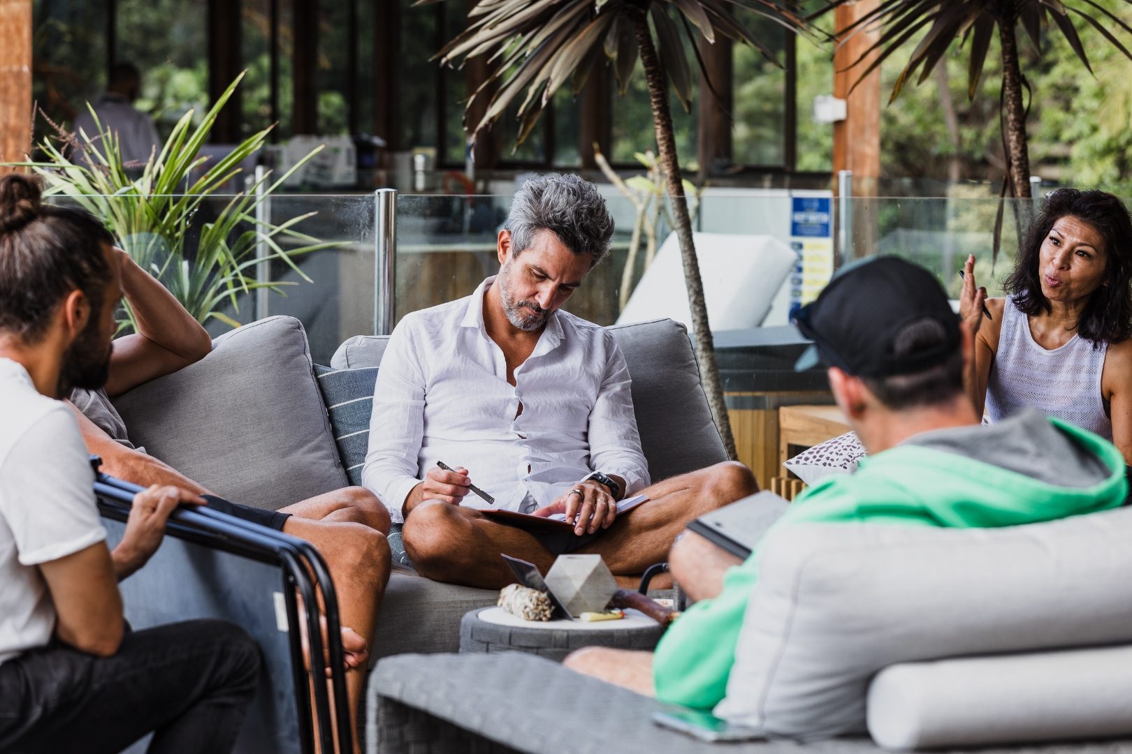 A small group in easy conversation on a lounge deck among palms