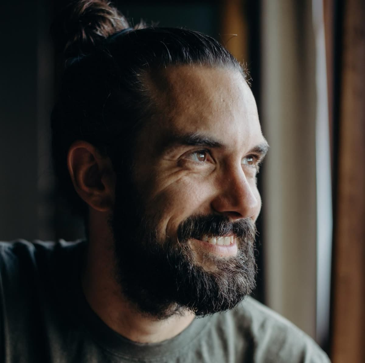 Portrait of Dan Kurlapski looking out a window in warm light